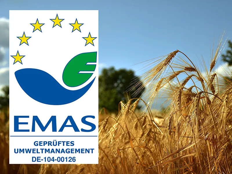 Das Siegel des EMAS Zertifikats auf einem Foto eines goldenen Gerstenfeldes vor blauem Himmel