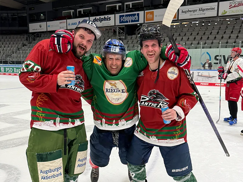 Drei Männer in Eishockeyausrüstung lachend